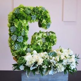 Буква «G» из живых цветов на подставке