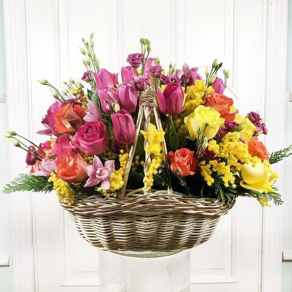 Корзина цветов с мимозой, розами, тюльпанами, орхидеями и зеленью